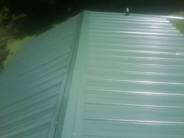 New green metal panels meeting at the ridge of a roof — Flat Roof Repair work by our crew in Rimforest