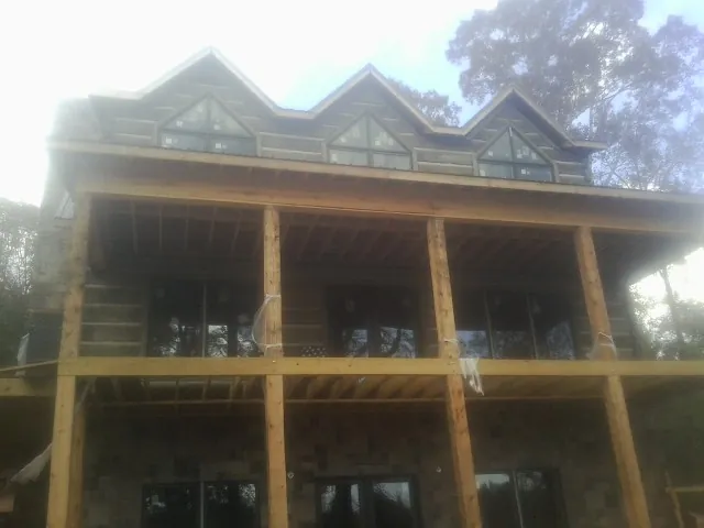 Dormers and porch framing on a large log home under construction — Roof Coating work by our crew in Rimforest