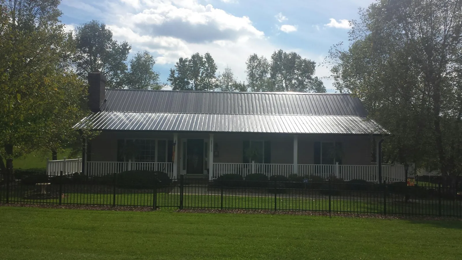 Gray metal roof on a brick ranch with a full width front porch — Gutter Guard Installation work by our crew in Rimforest