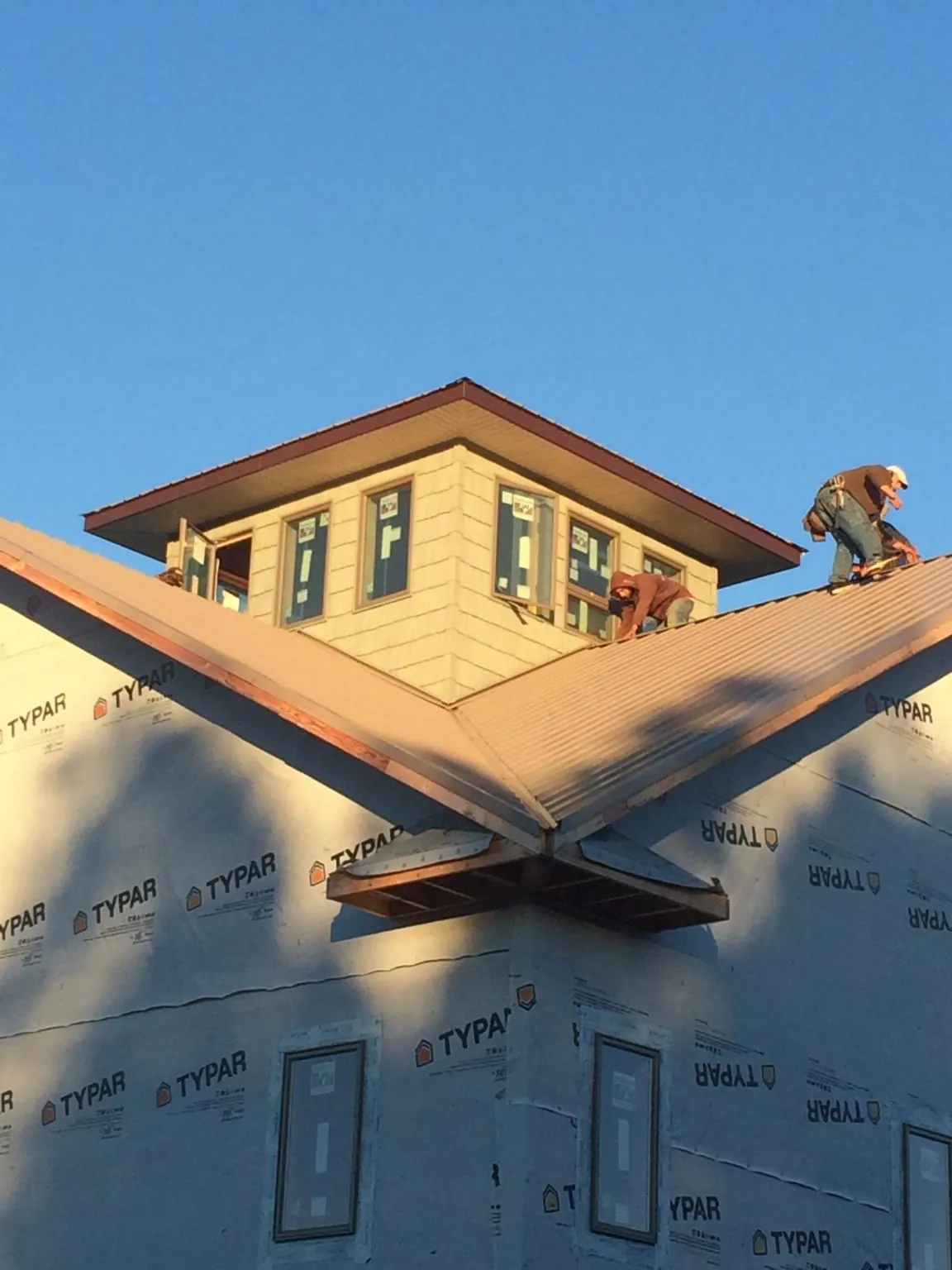 Roofers working around a rooftop cupola on a new metal roof at sunset — Roof Waterproofing in Rimforest by Roofing Brothers